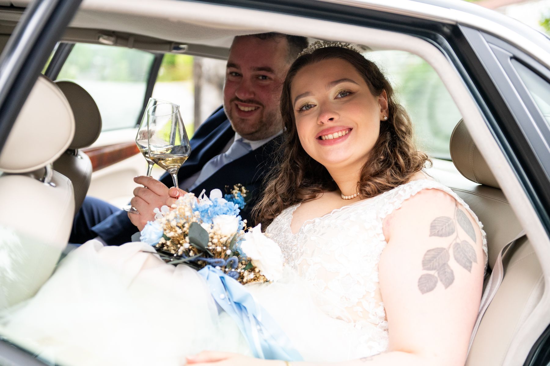 Brudeparet skåler med champagne i baksetet på Jaguaren
